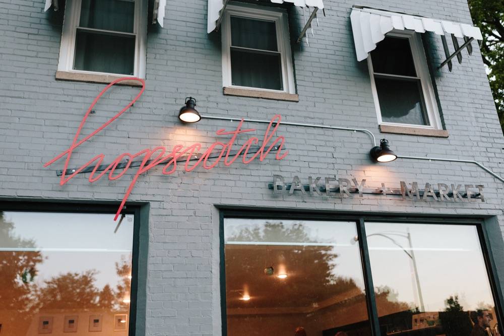 The front of Hopscotch Bakery - a gray two story building with large windows along the bottom.