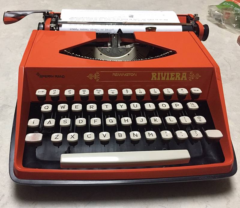 a close up image of a red typewriter with a sheet of paper in it.