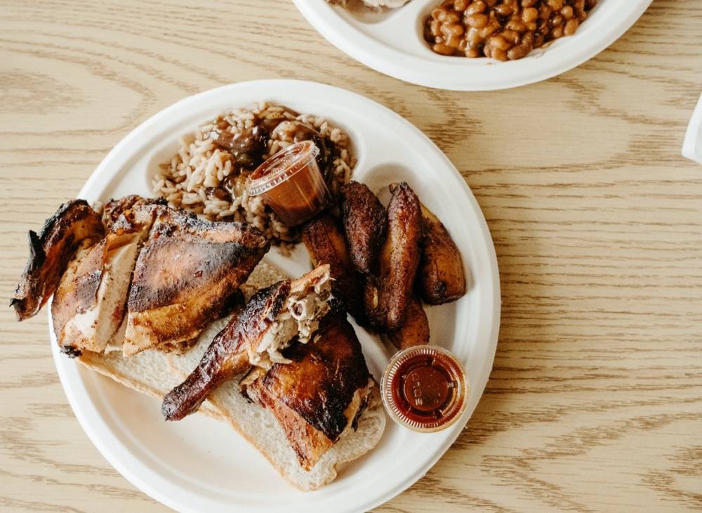 A plate of jerk chicken at Caribbean Grill, served with plantains and rice and peas. 