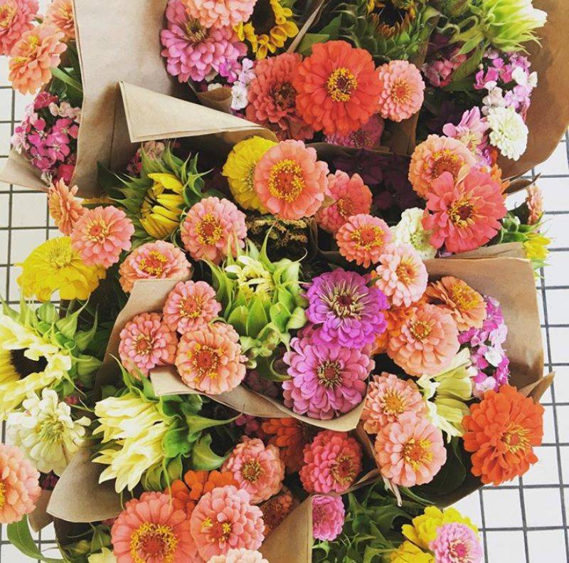 Bouquets of pink, orange, and peach flowers, wrapped in brown paper.
