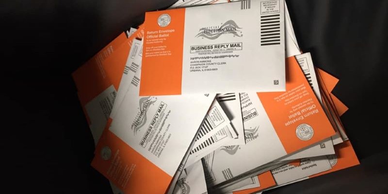 A pile of orange and white envelopes in a dark box.