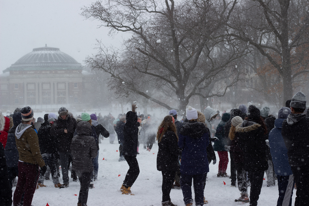 A snowball fight on the U of I quad. A large crowd of students in winter gear are throwing snowballs. Photo by Jorge Murga. 