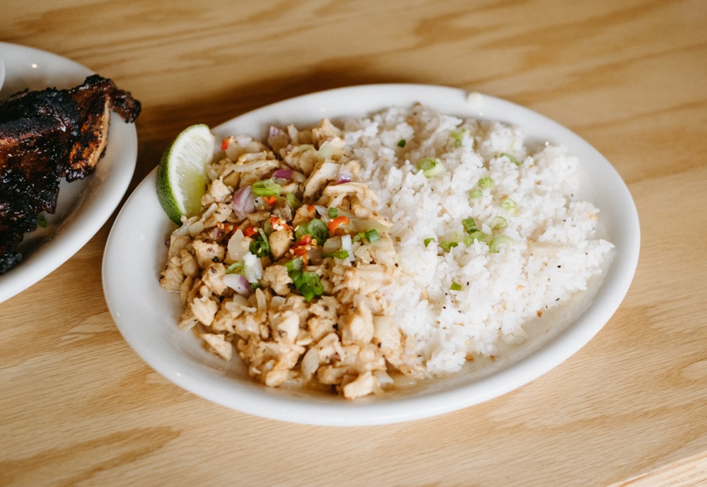 A plate of chicken and pork, a serving of white rice, and a lime