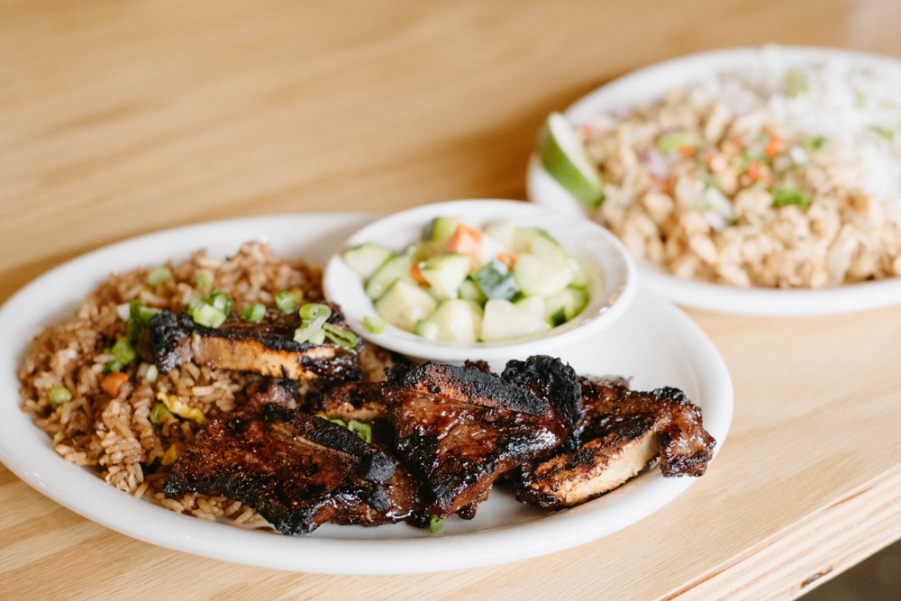 A plate of short ribs, fried rice, and a bowl of cucumber salad
