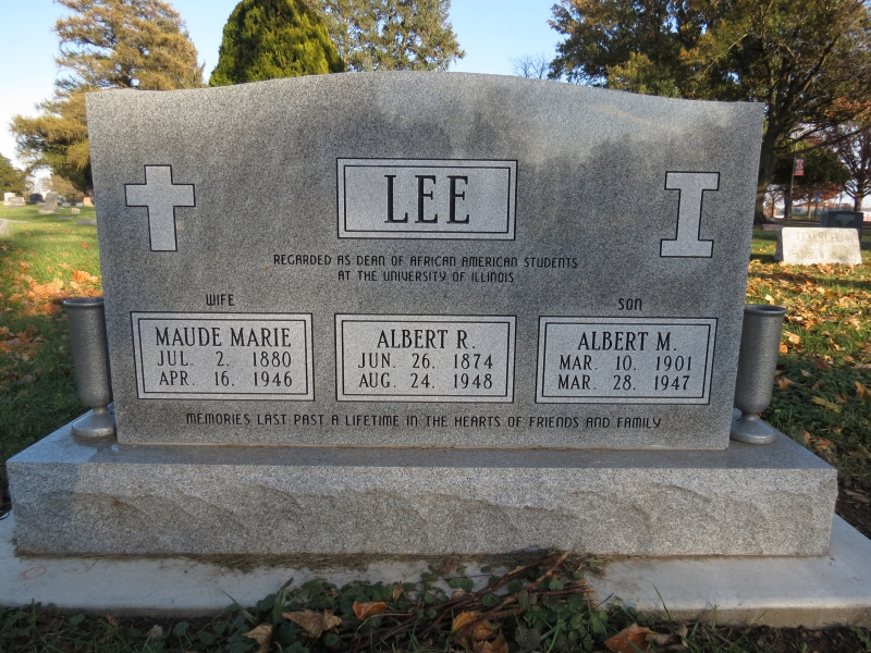 A wide, gray, rectangular headstone. The name Lee is inscribed in the center, with a block style cross on one side and a block I on the other. Below are three lighter gray square bearing the names of the three people buried there: Maude Marie, Albert R., and Albert M. Photo from The Public i. 
