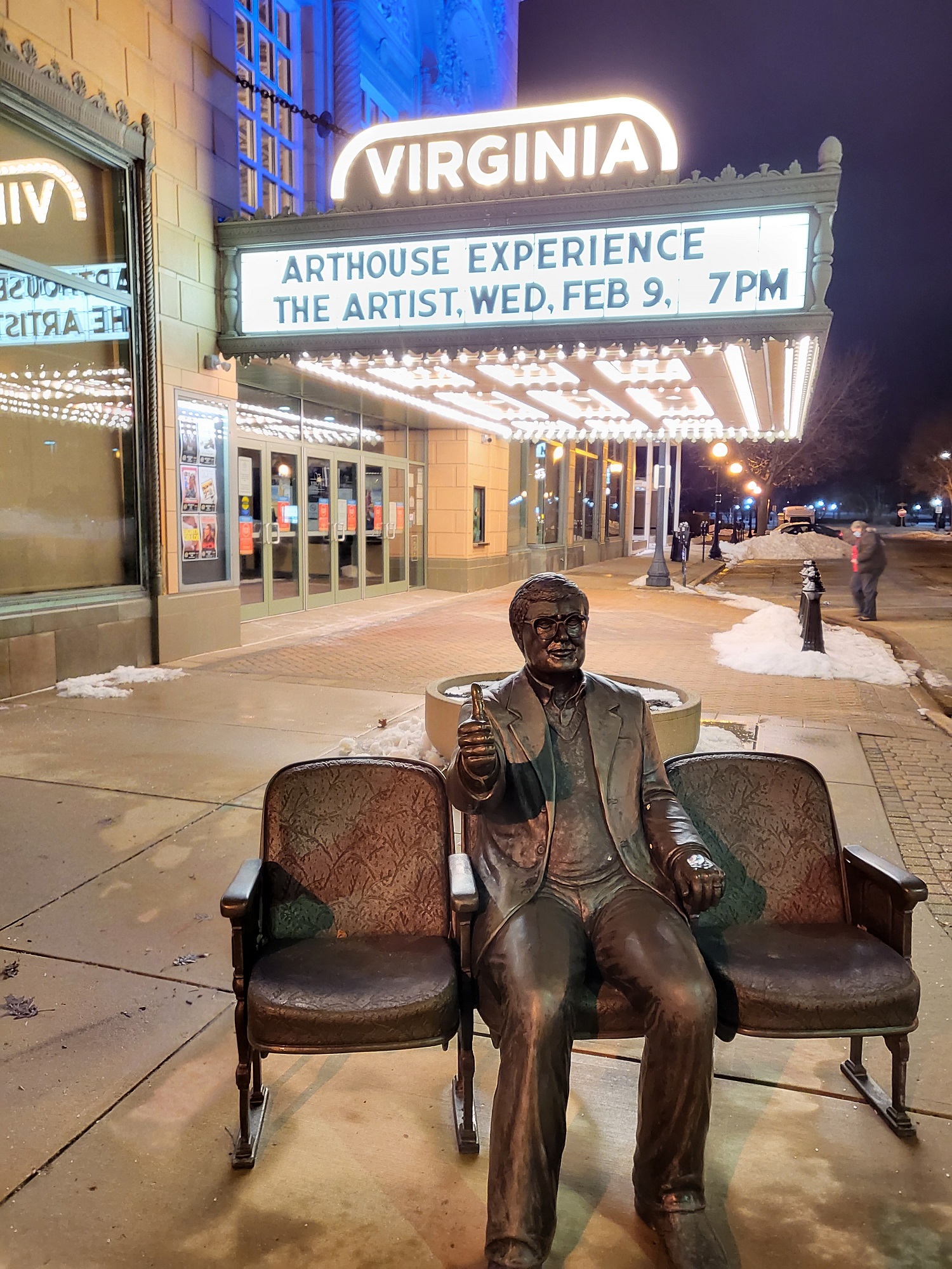 Photo of the Roger Ebert statute in front of the Virginia Theatre with a marquee for 