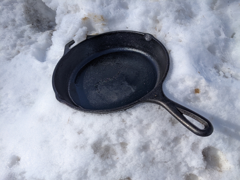A black cast iron pan is sitting in the snow. Photo by Tom Ackerman.