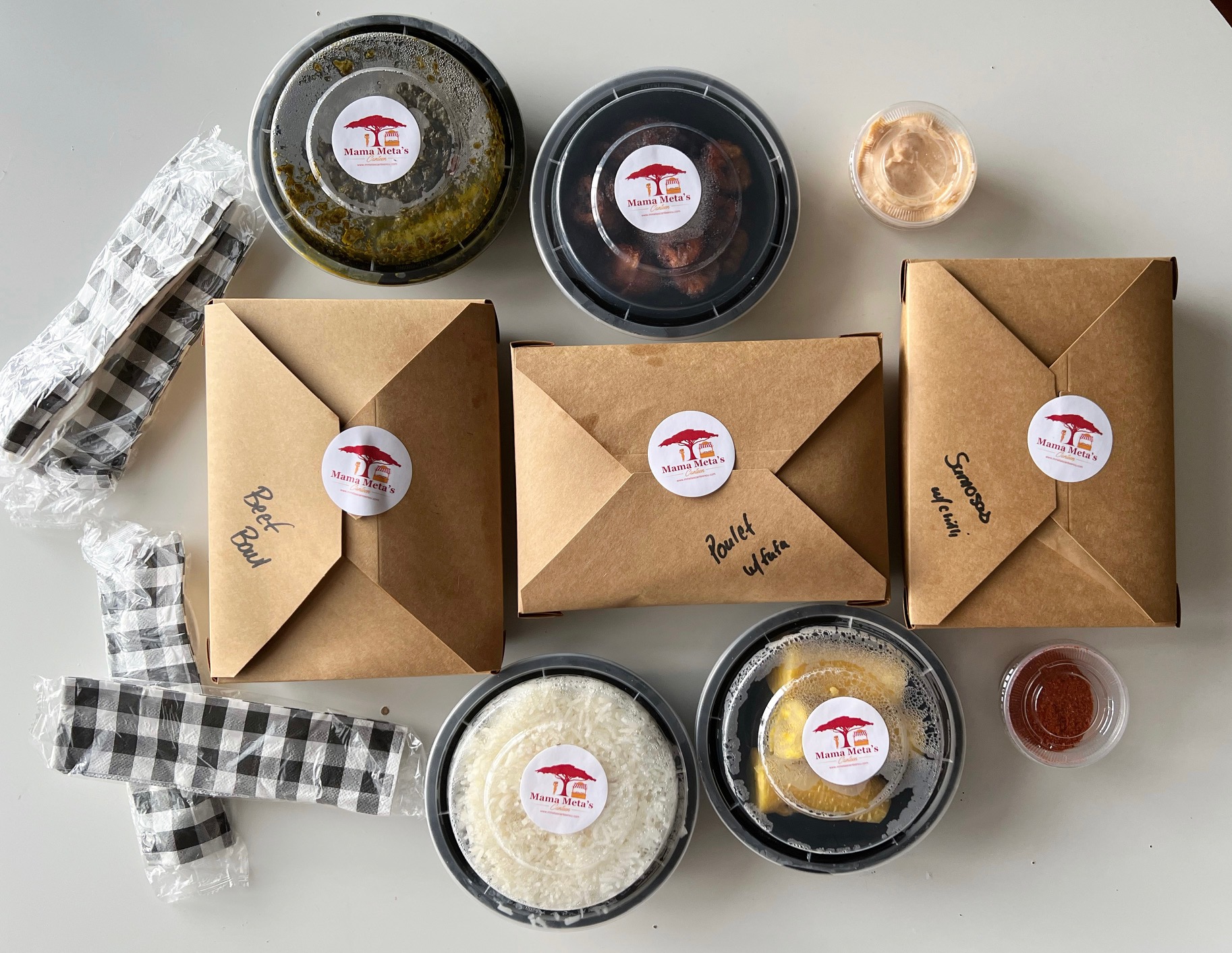 On a white table, the author's lunch order is spread out in cardboard rectangle boxes and circular plastic containers. Photo by Alyssa Buckley.