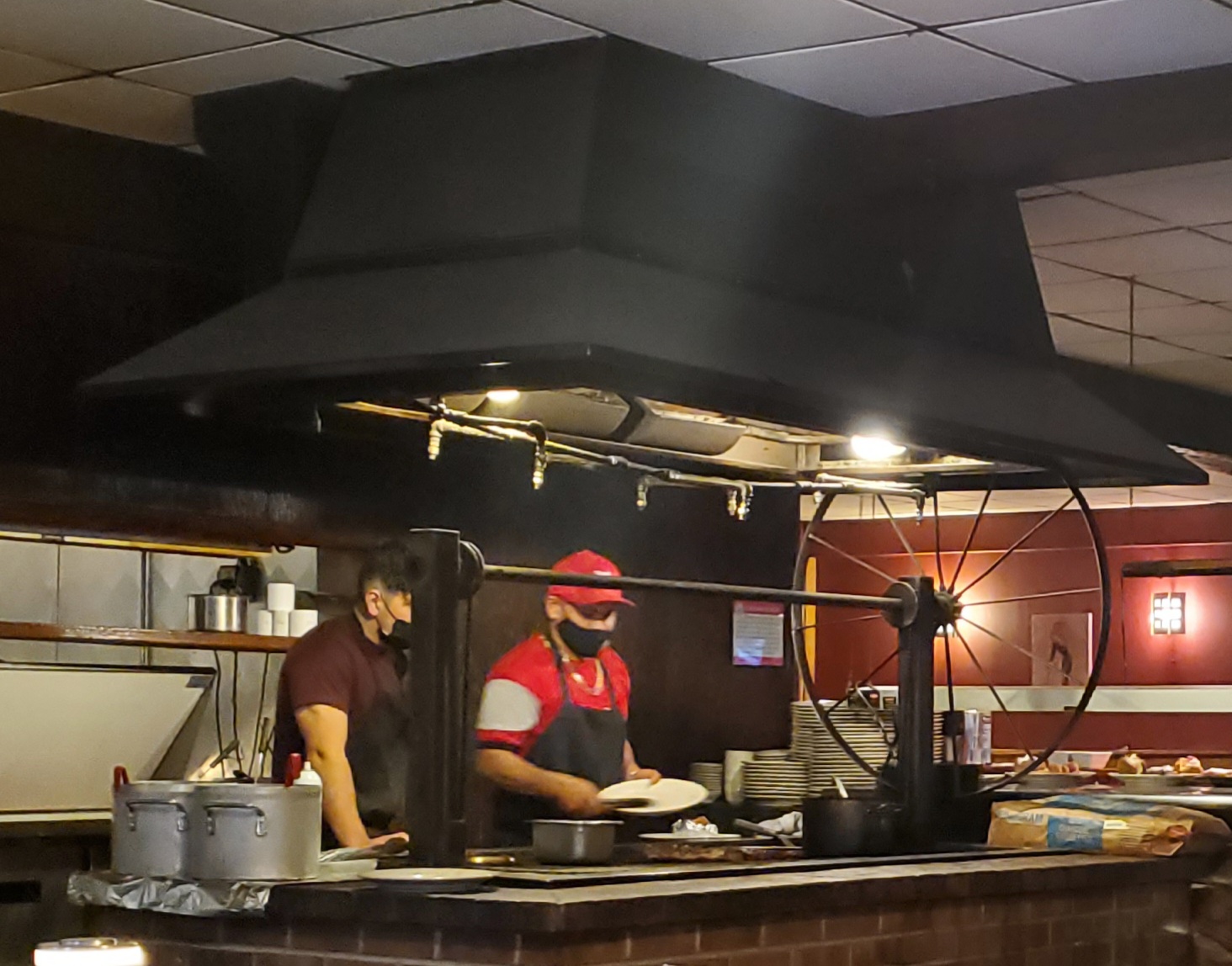 An open grill inside Possum Trot has two masked staff cooking food. Photo by Carl Busch.