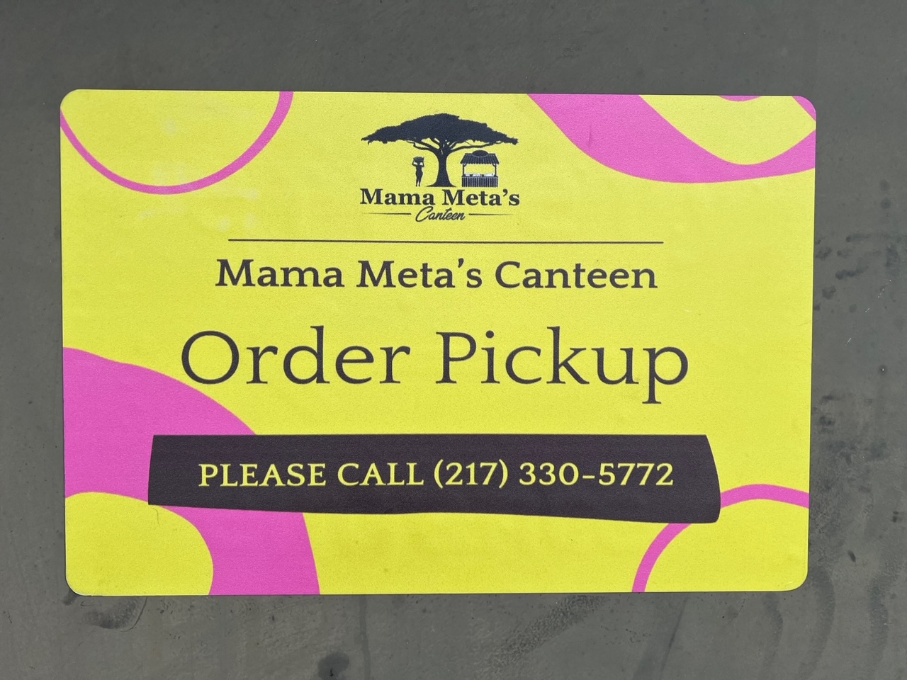 On a gray background, a yellow sign for Mama Meta's Canteen reads 