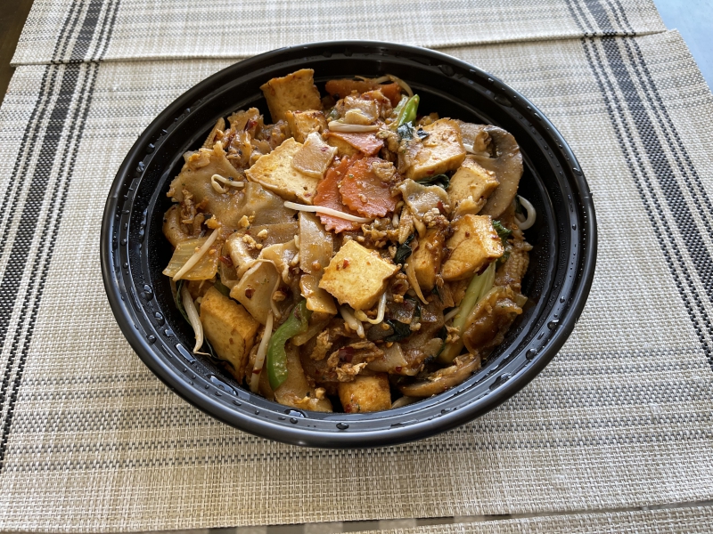 A photo of pad kee mao from Thara Thai in a black takeout bowl. Photo by Shrivatsa Ravikumar.