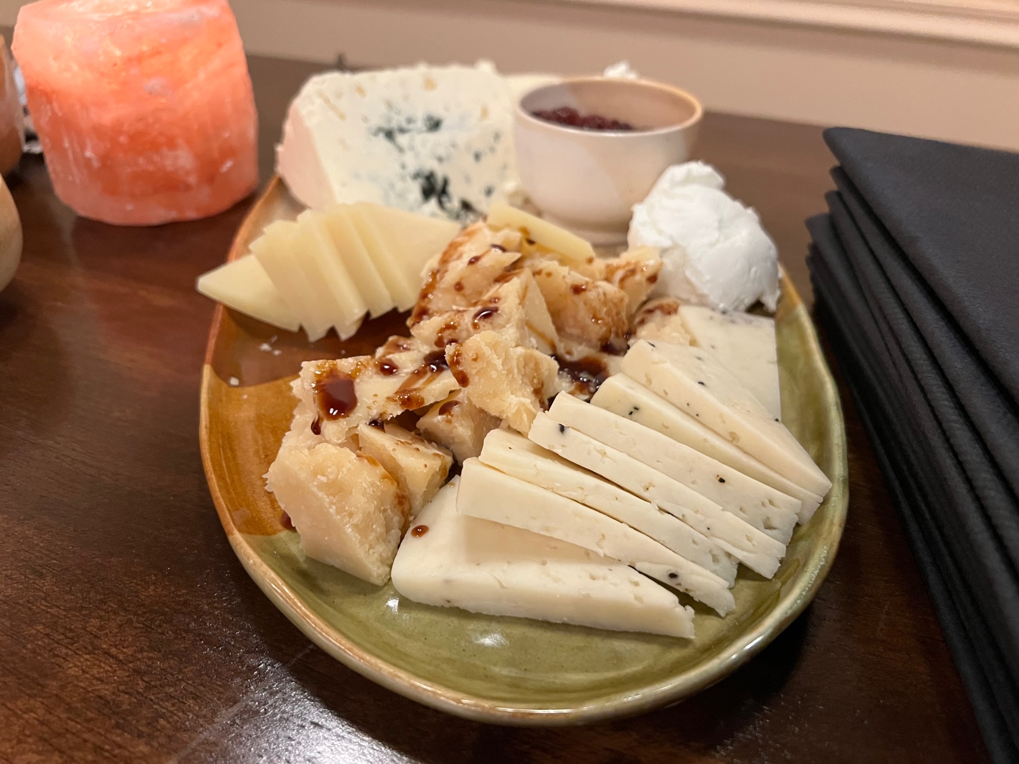 On a green-gray platter, there are a variety of cheeses. Photo by Alyssa Buckley.