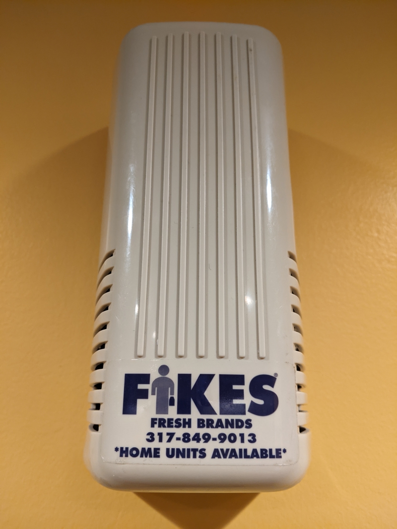 A white plastic case hanging on a yellow wall. It says FIKES fresh brands in blue lettering. Photo by Tom Ackerman.