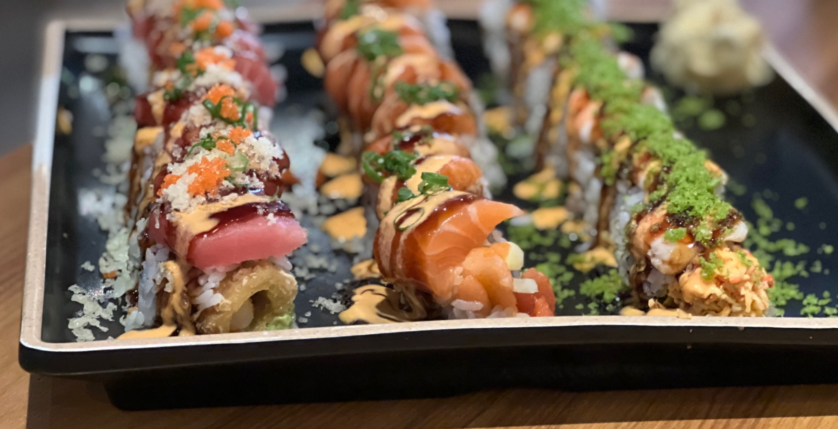 On a black plate inside Sakanaya on Green Street, there are three rolls. On the far left, the playgirl roll, kamikaze in the center, and crab roll on the right. Photo by Alyssa Buckley.
