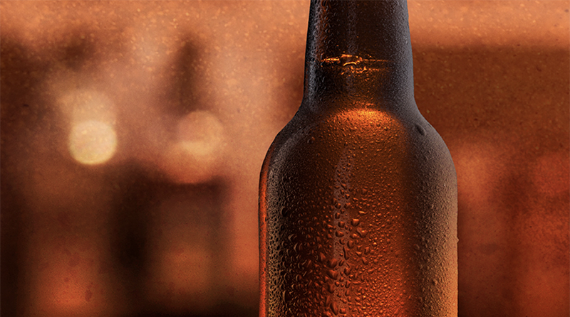 Sepia toned photo of a sweating bottle of beer. 