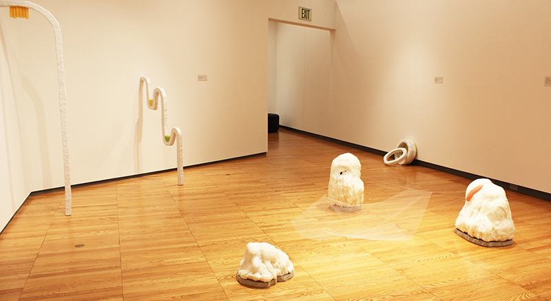 A series of white boulders on the floor and tubes with colored elements attached.. 