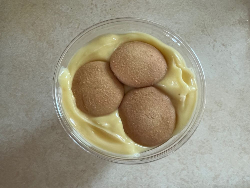 A round clear container filled with light yellow pudding. Three light brown circular wafer sit on top of the pudding. Photo by Julie McClure.