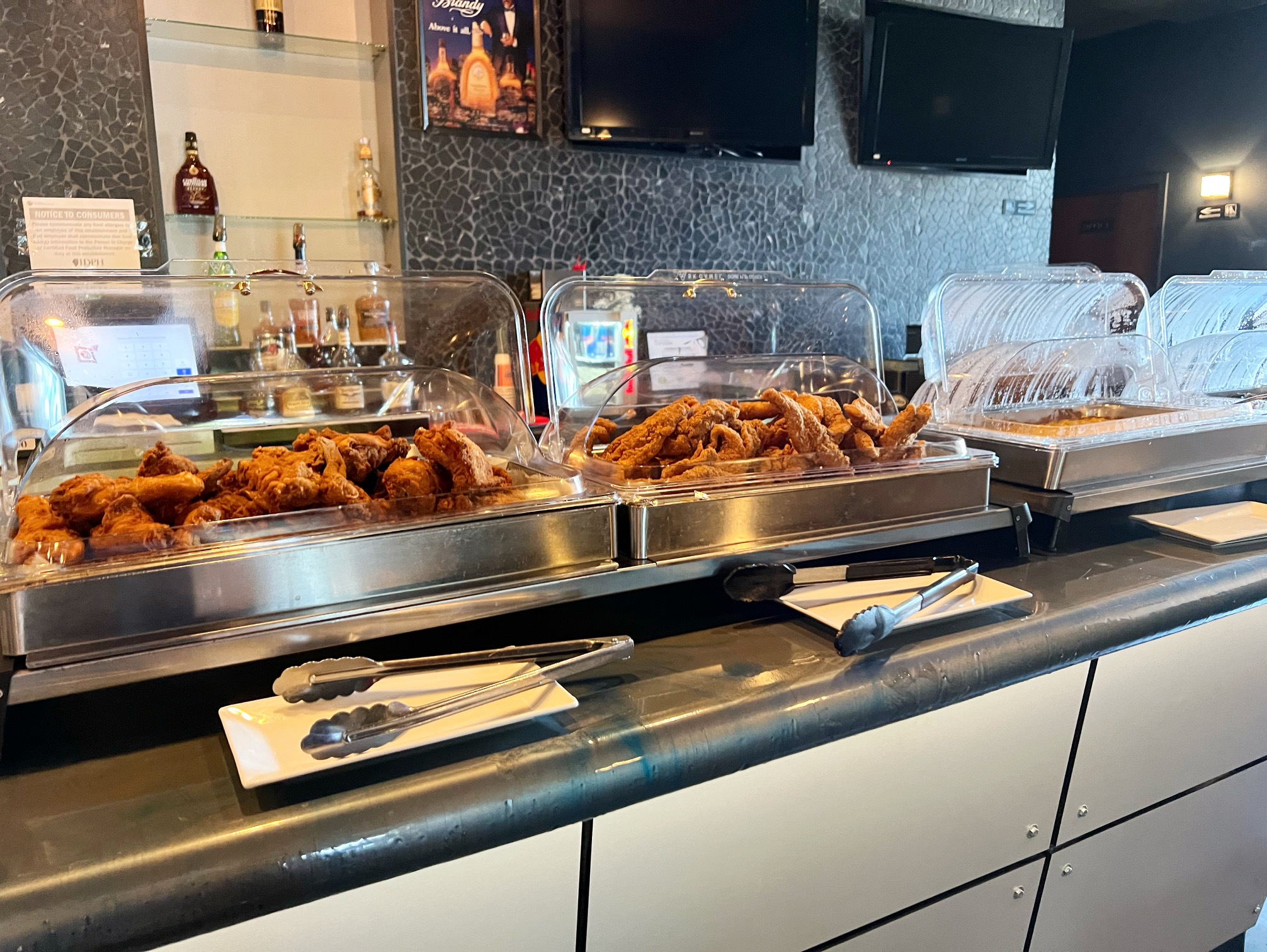 On the buffet at Neil St. Blues, there are large trays of fried chicken, fried catfish, and other dishes in shiny metal containers. Photo by Alyssa Buckley.