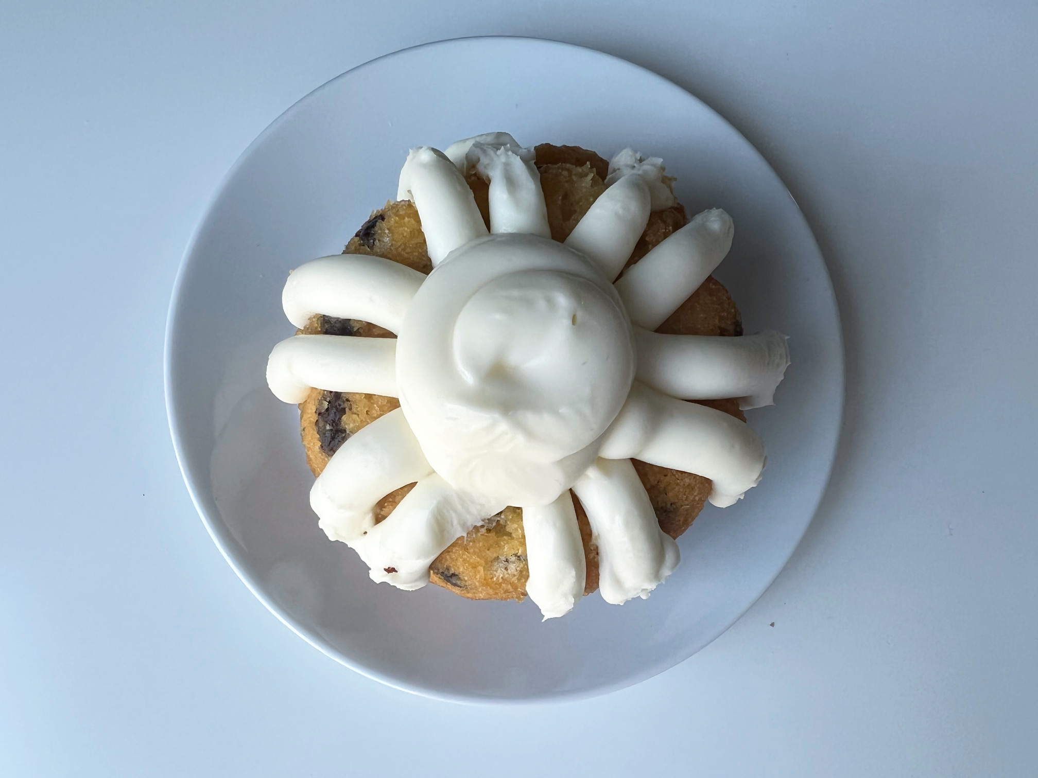 On a white plate on a white table, a chocolate chip bundtlet from Nothing Bundt Cakes is uncut and uneaten. Photo by Alyssa Buckley.