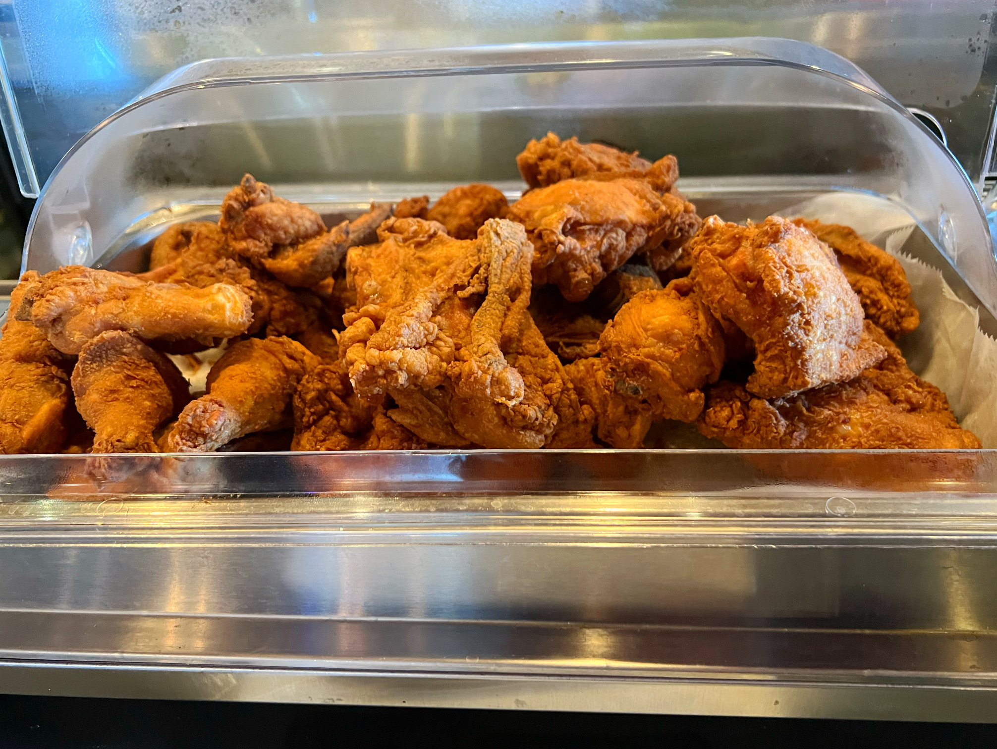 In a shiny metal pan, there is an overflowing amount of fried chicken. Photo by Alyssa Buckley.