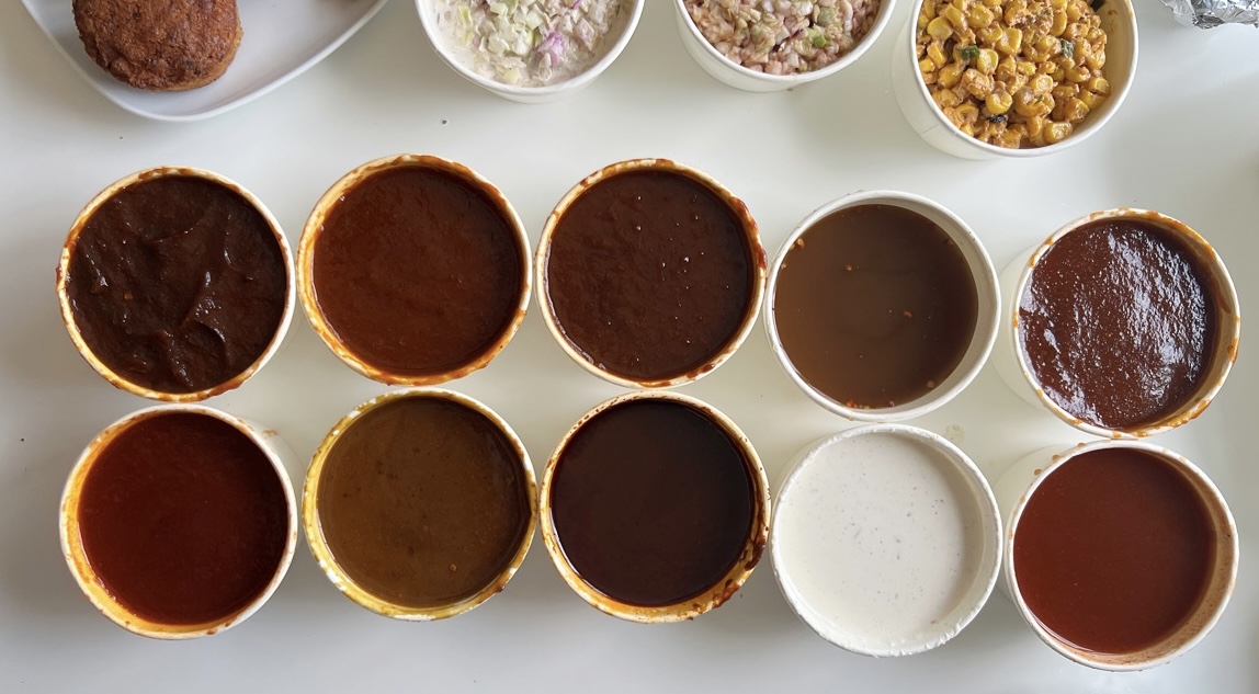Ten barbeque sauces from Black Dog are in white cups with no lids in two rows of five cups. Photo by Alyssa Buckley.
