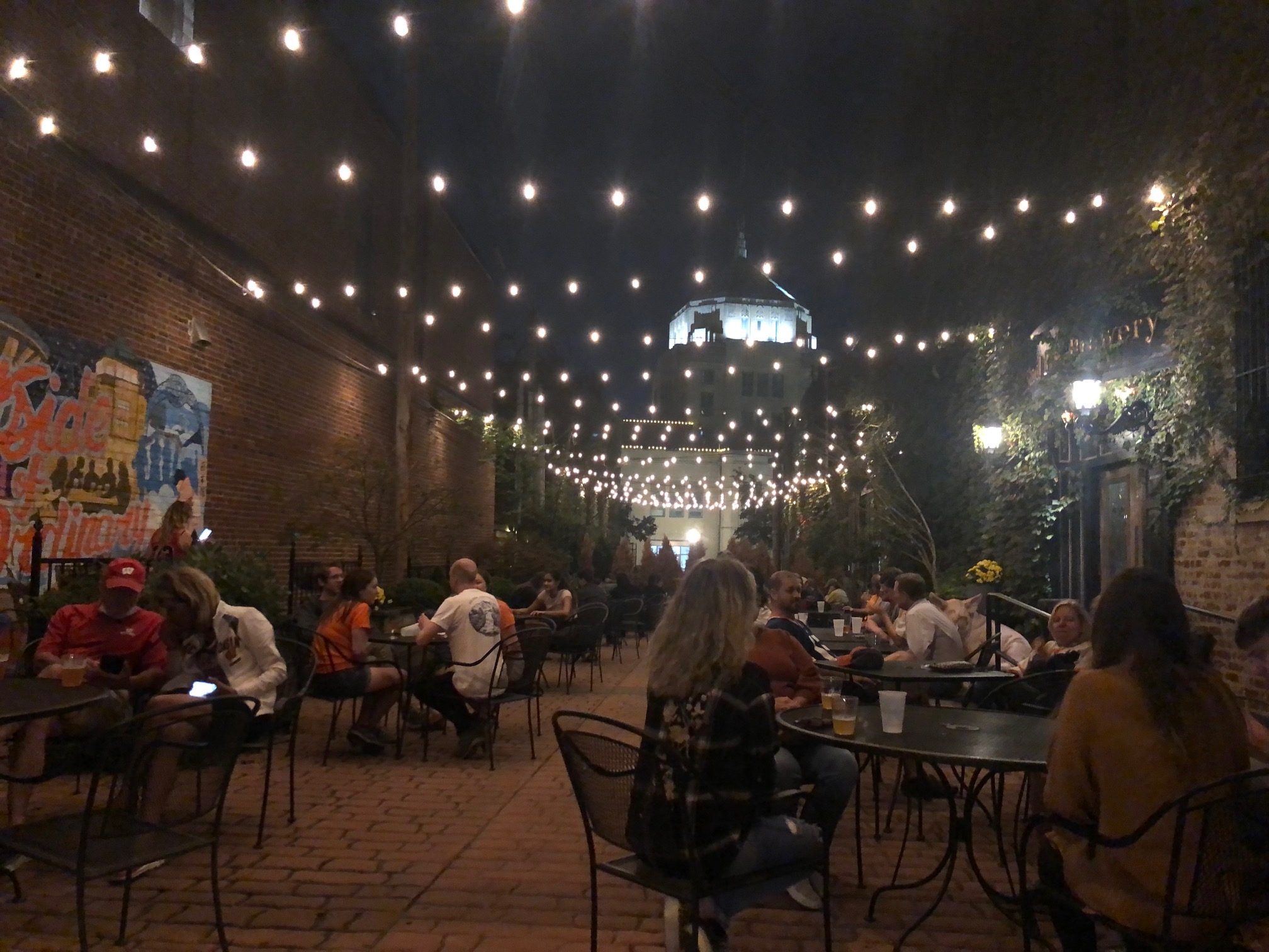 Outside at night, people enjoy drinks under string lights at Blind Pig in Downtown Champaign. Photo by Alyssa Buckley.