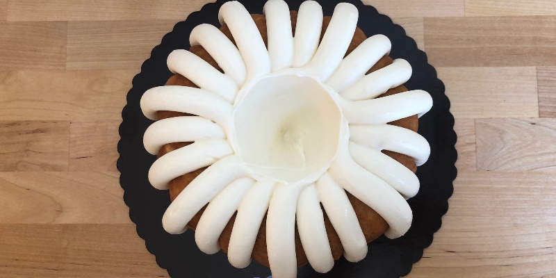 On a butcher block counter, there is a vanilla bundt cake with cream cheese frosting stripes from Nothing Bundt Cakes in Champaign. Photo by Alyssa Buckley.