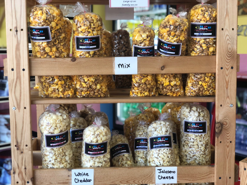 Inside the CBPB Popcorn Shop, there is a wooden stand holding bags of specialty popcorn. Photo by Alyssa Buckley.