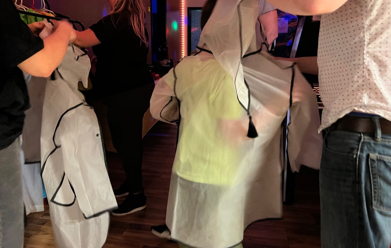 Two children are being helped into clear child-sized ponchos at Rage Room Champaign. Photo by Alyssa Buckley.