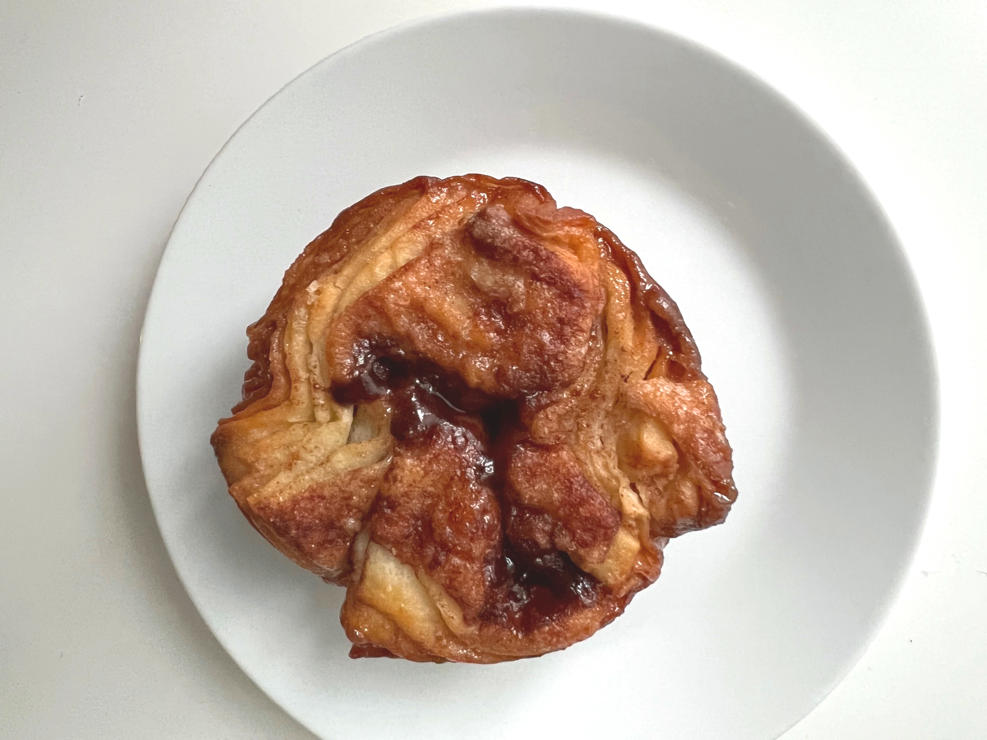On a white plate on a white table, there is a koiugn amann from Six Red Chairs Bakery. Photo by Alyssa Buckley.