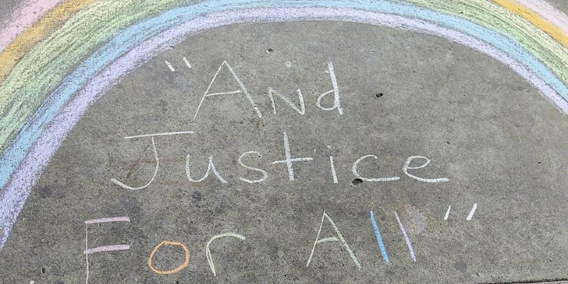 A chalk drawing of a rainbow, with the words And Justice for All written underneath.
