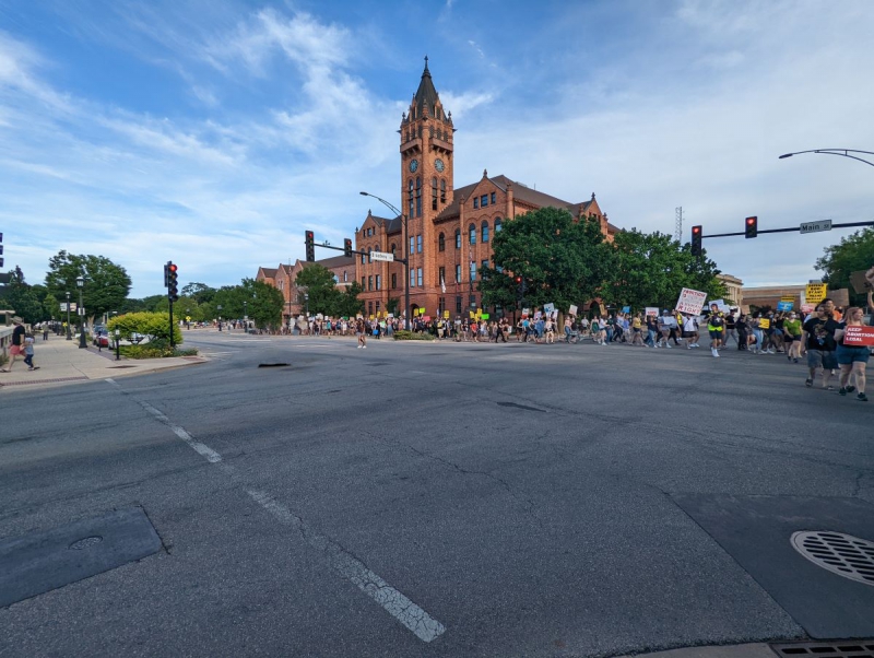 The protesting crowd wraps around the first intersection of the march, stretching back all the way to the courthouse, a red brick building with a clock tower. Photo by Brandi MV McCoy.