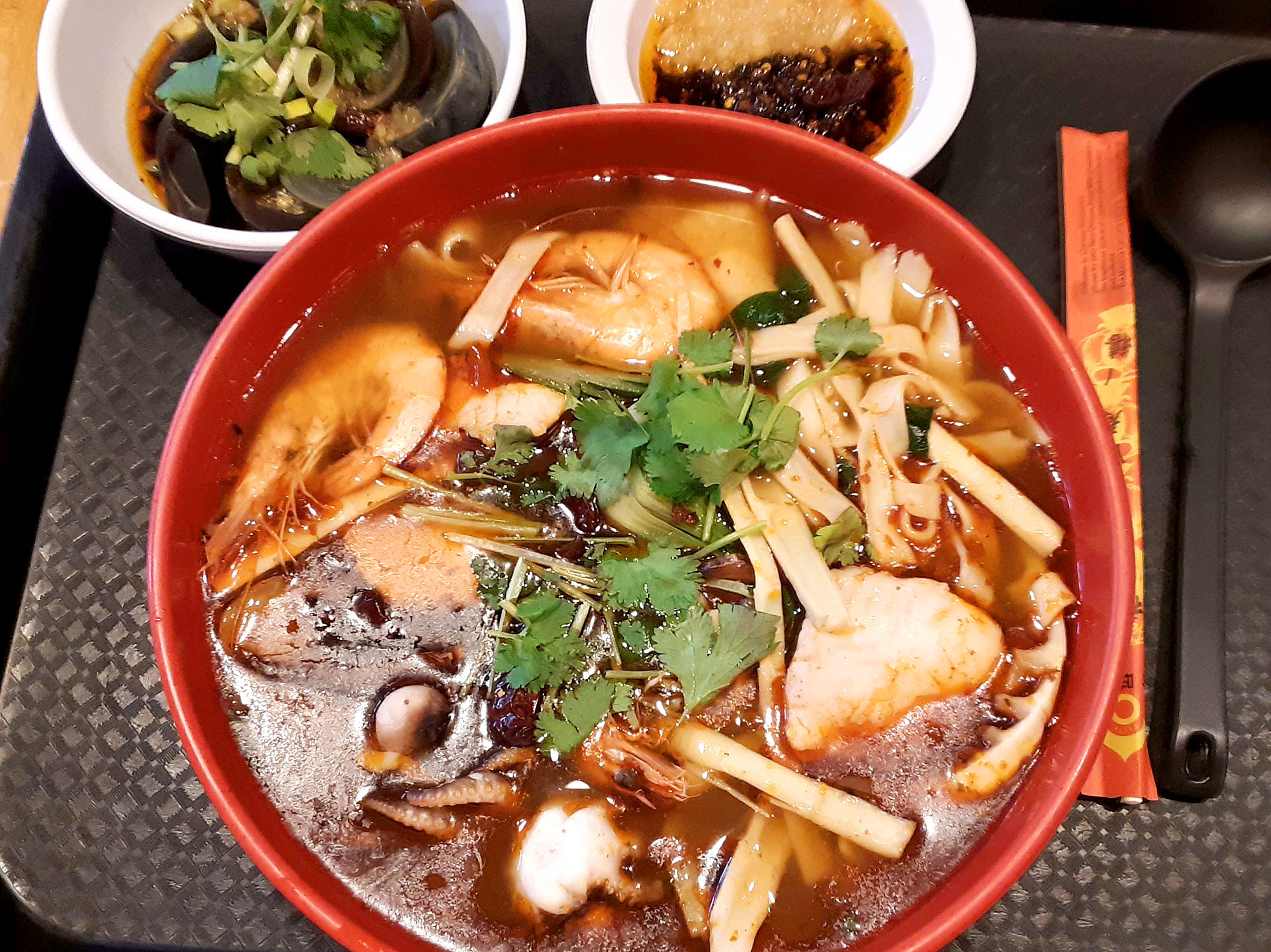 A huge bowl of seafood ramen with two small sides. Photo by Paul Young.