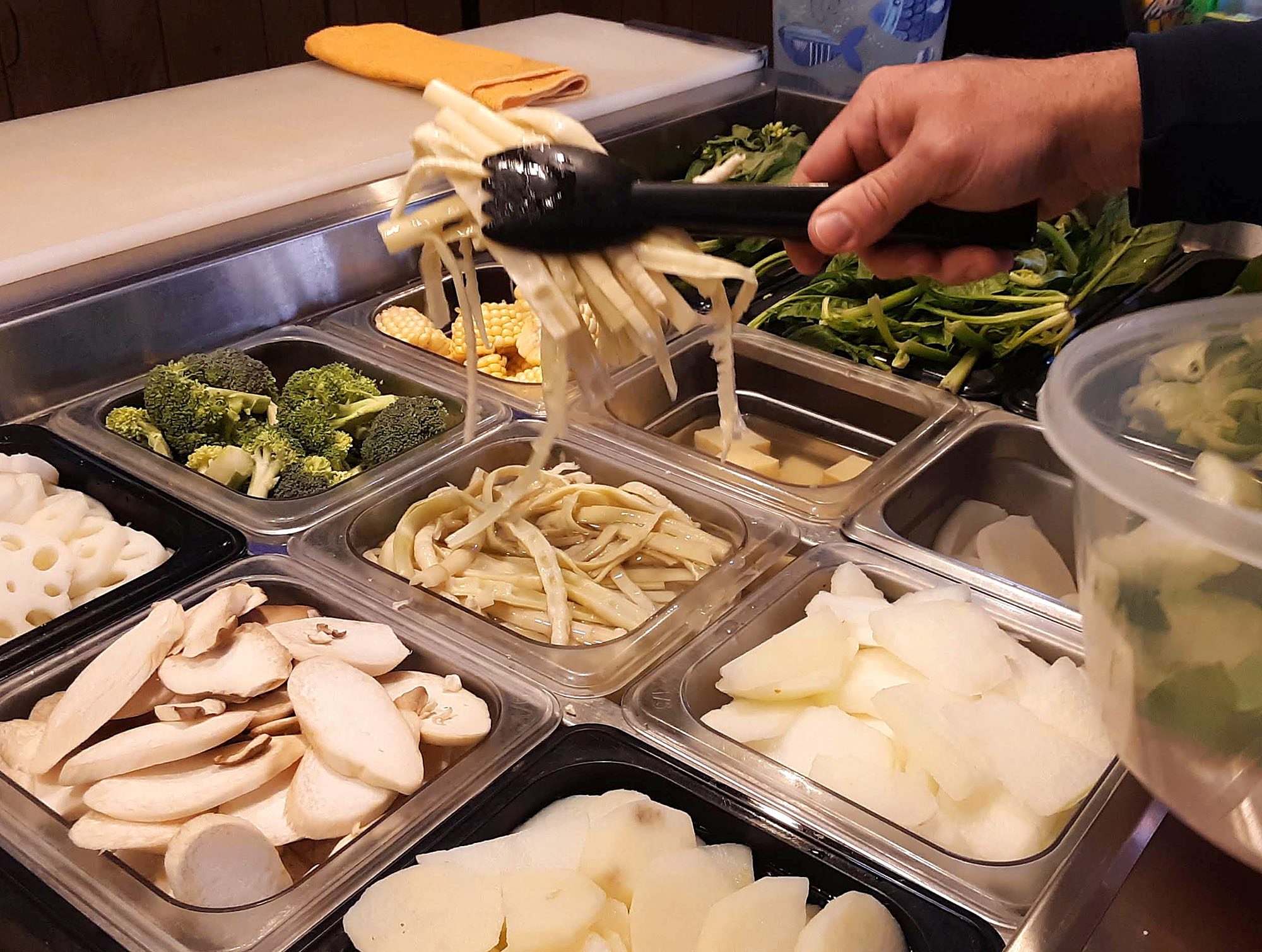 Full metal containers at Spicy Tang allow diners to choose vegetables to add. Photo by Paul Young.