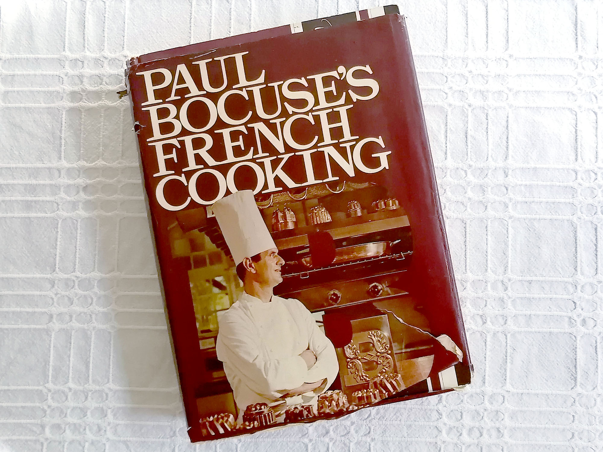 The cover of a used book titled â€œPaul Bocuseâ€™s French Cookingâ€ with torn cover. Photo by Paul Young.