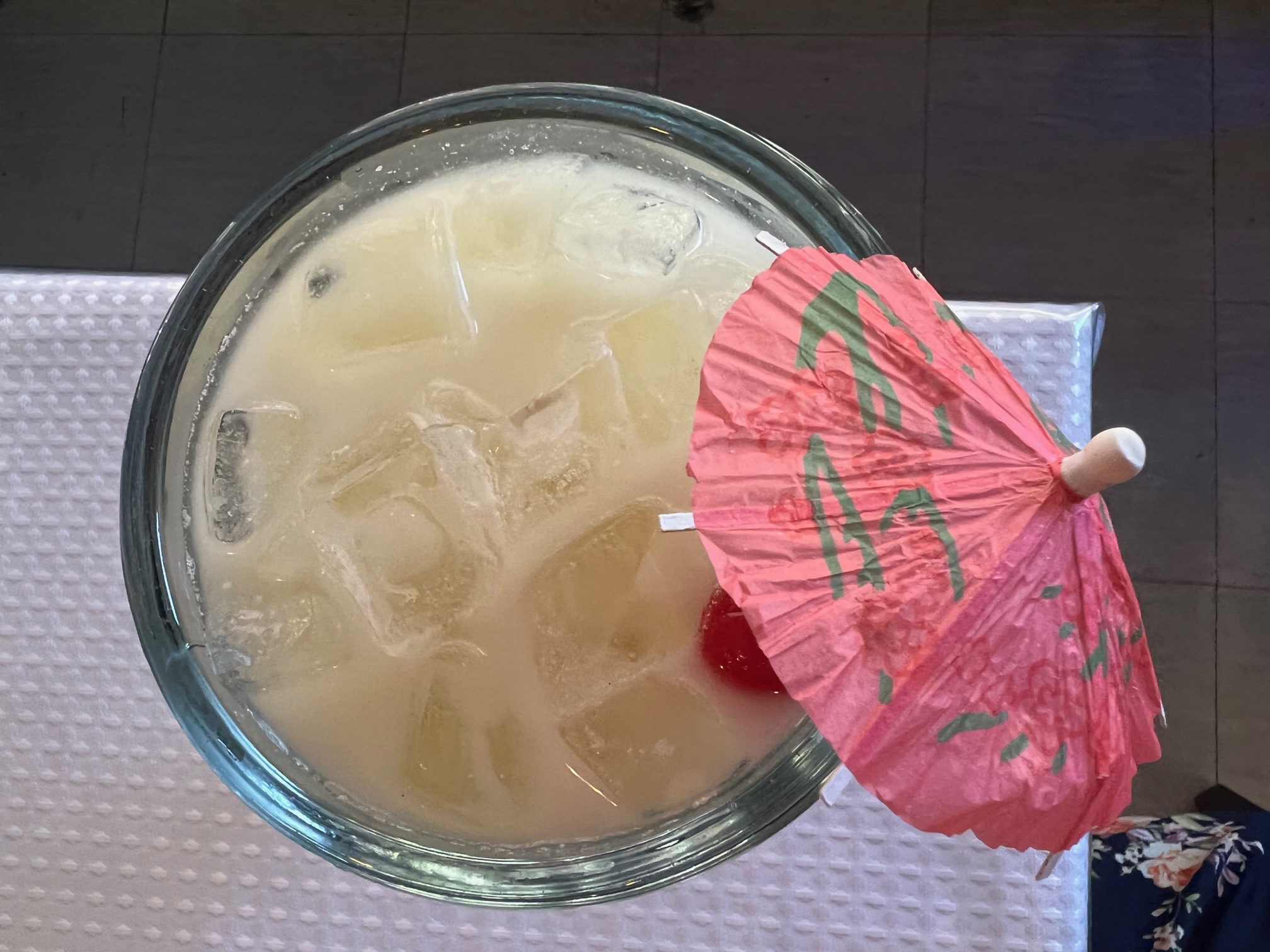 An overhead photo of a piÃ±a colada margarita at La Bahia Grill in Champaign. The white margarita is in a glass goblet with a red berry and a pink drink umbrella. Photo by Alyssa Buckley.