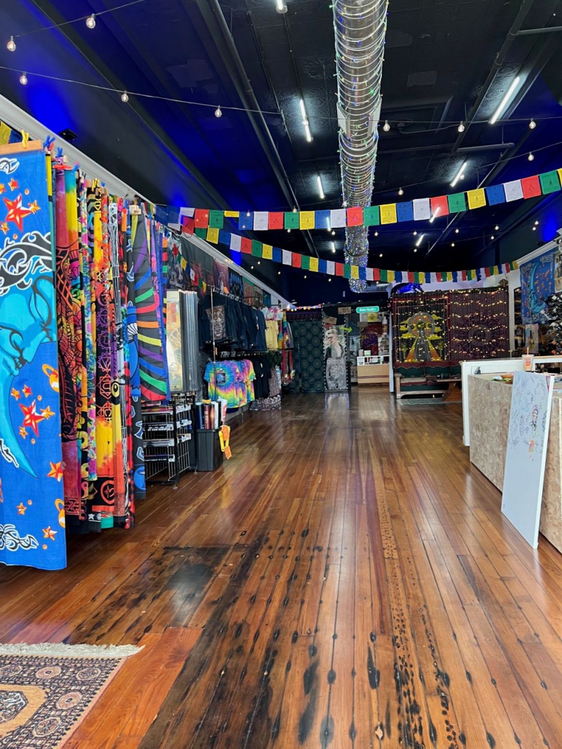 The inside of Mother Murphy's. There are tapestries, posters and clothing hanging along the left wall. Colorful flags stretch across the ceiling. The floor is wood, and there is a counter on the right. Photo by Julie McClure.