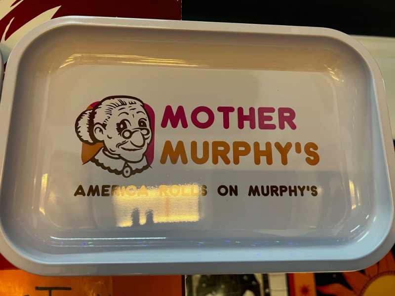 A rolling tray that is white with an icon of an old women with glasses and white hair in a bun. It says Mother Murphy's in pink and orange lettering, then America Rolls on Murphy's along the bottom in black lettering. Photo by Julie McClure.