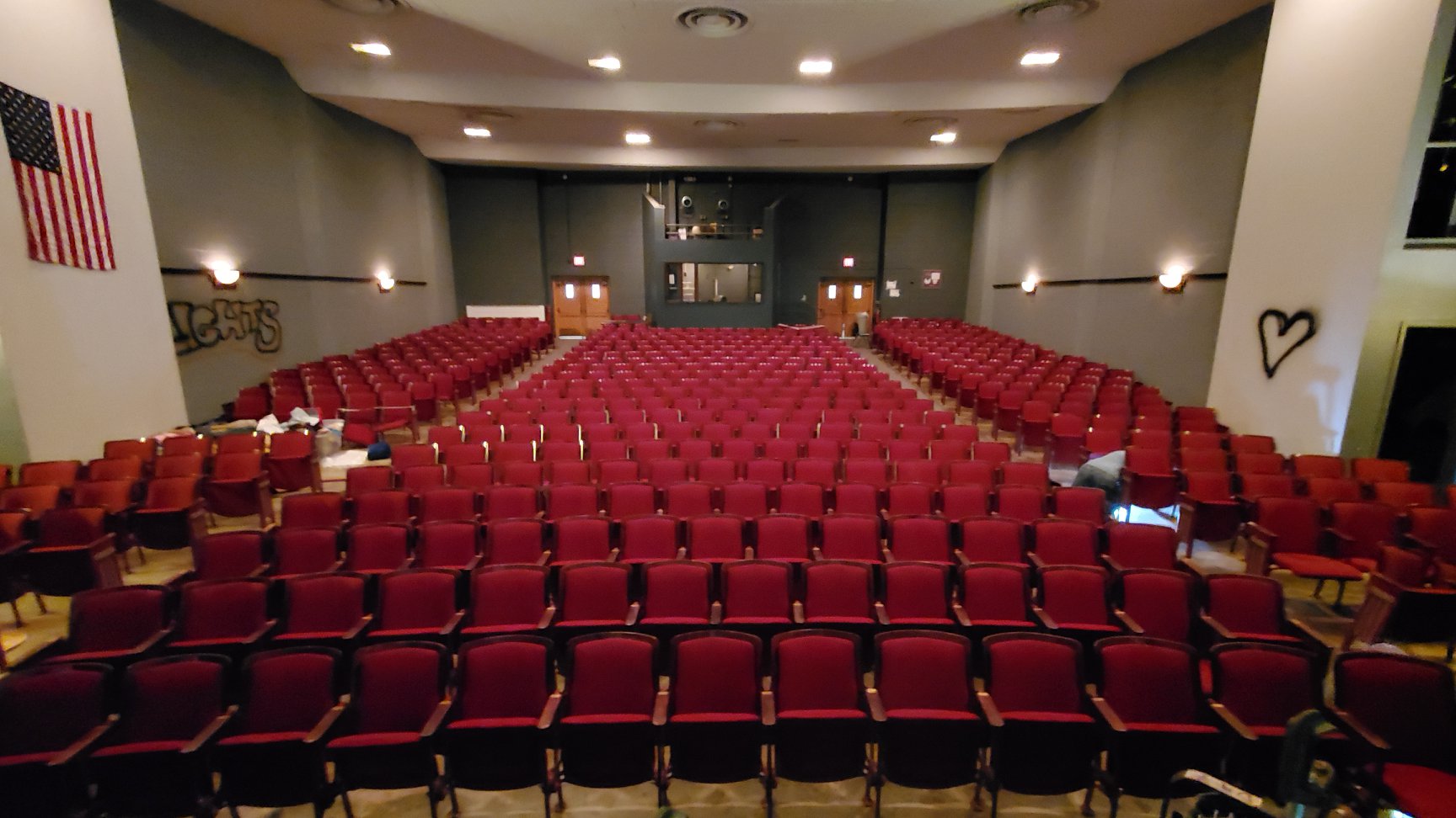 View from the stage of an empty theater. The theater seats are red and upholstered. There are three sections, and they are positioned to be slightly curved toward the stage. Photo from the PACA Facebook page.