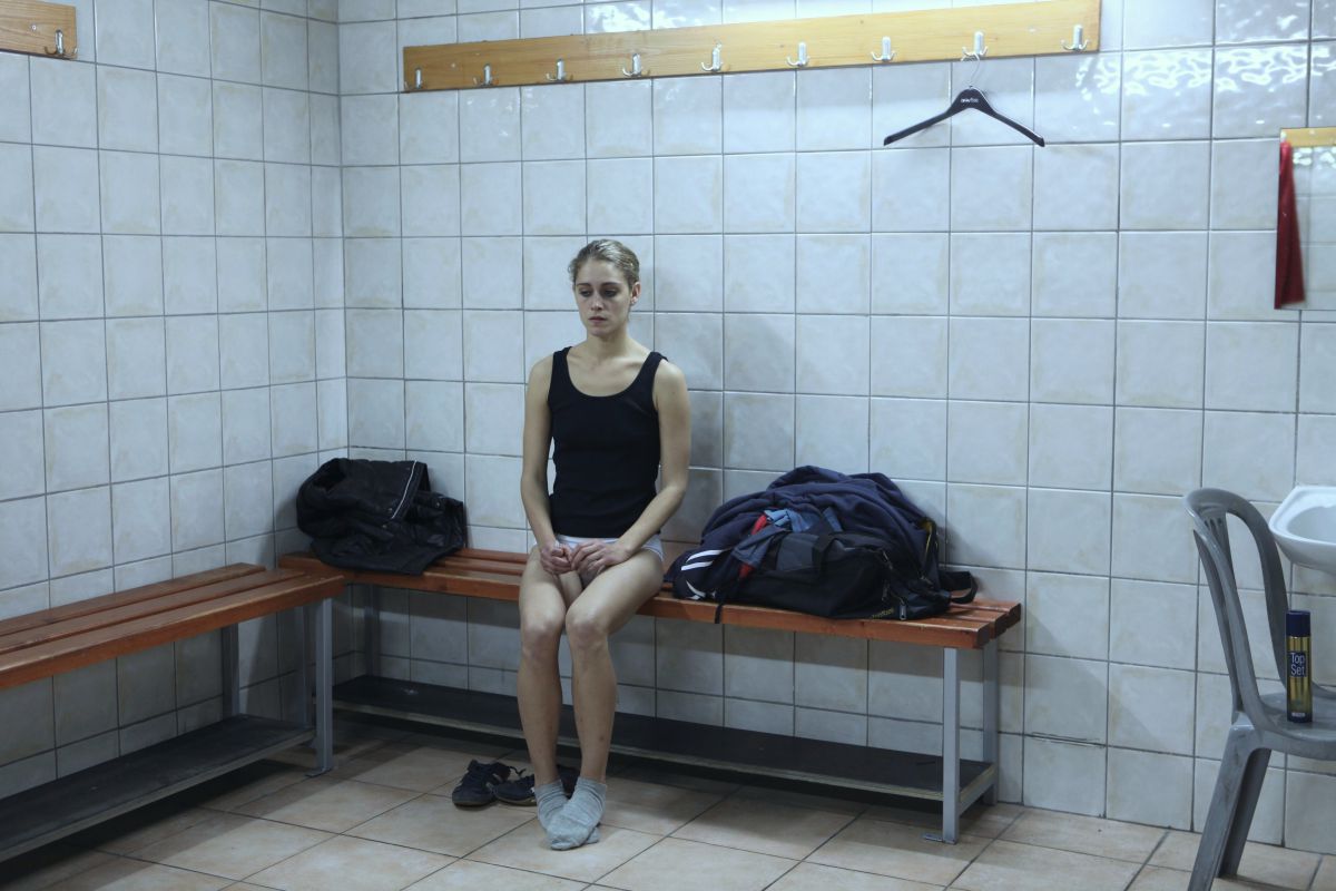 A woman sitting on a bench in the dressing room of a gym. She looks sad and lonely. Photo courtesy of Criterion Channel.