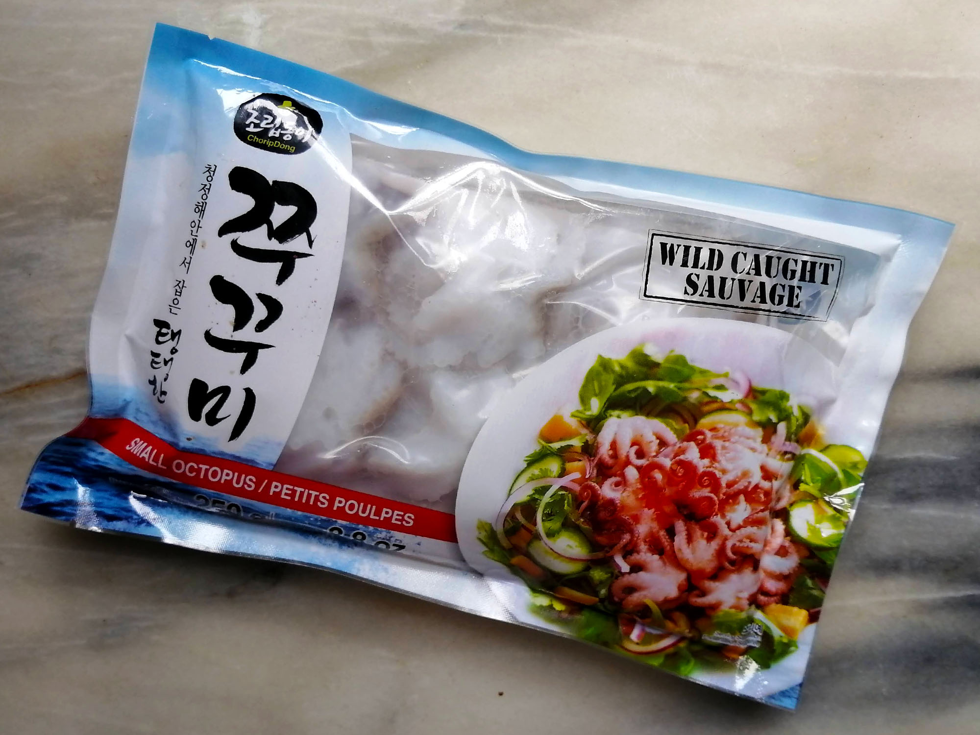 A package of imported frozen baby octopus with Asian writing; the words â€œwild caughtâ€ is prominently displayed in English and French. Photo by Paul Young.