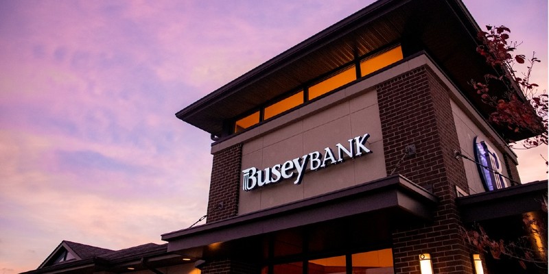 The top of a builing with light and dark brown siding, with the words Busey Bank in white lettering along the side