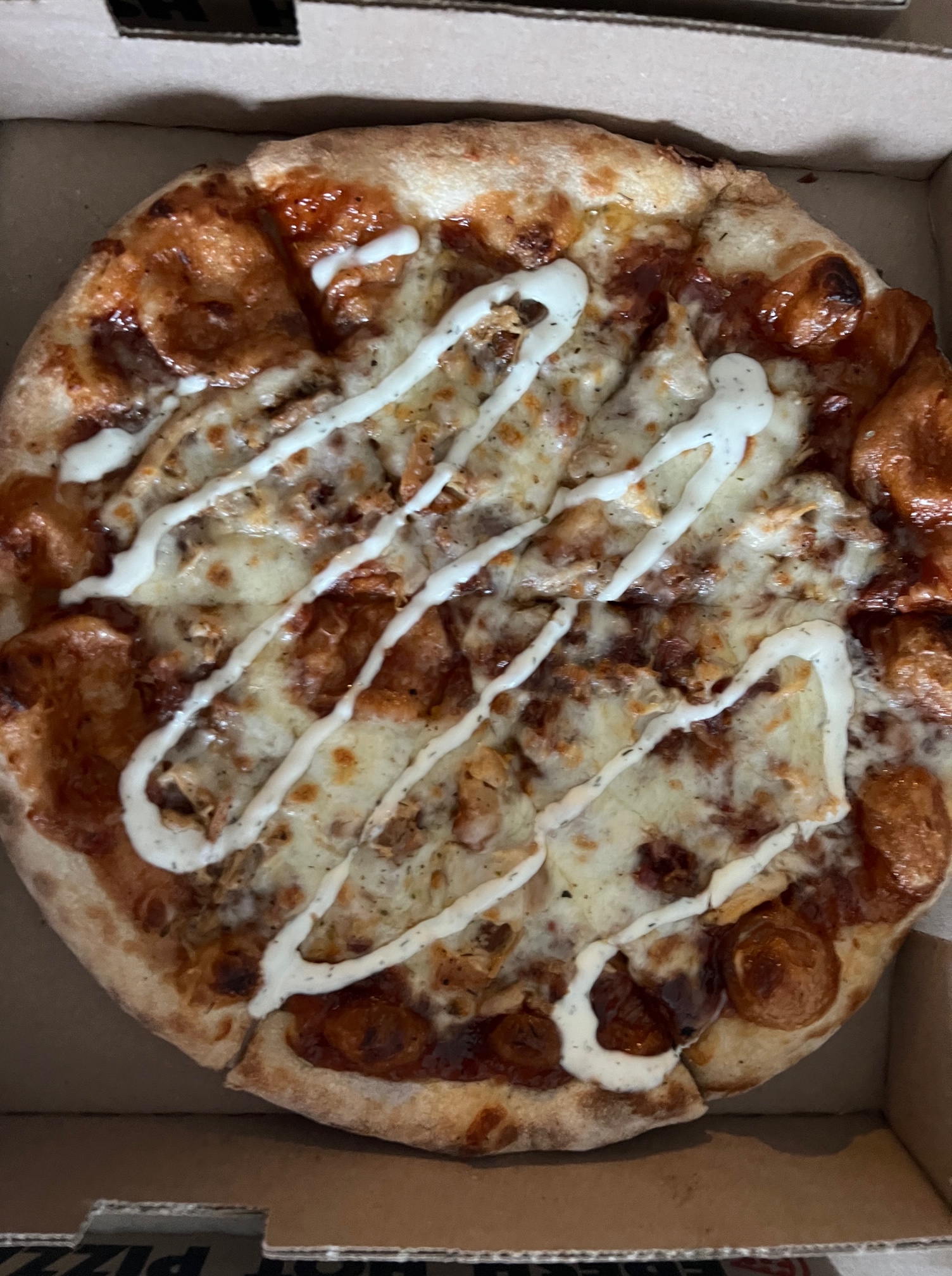 In a pizza box, there is a barbecue chicken pizza with a ranch drizzle. Photo by Alyssa Buckley.