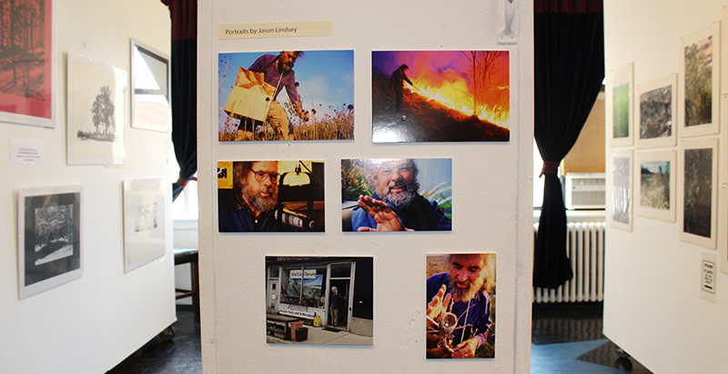 Installation of Monk in Retrospective at IMC, Urbana. A collection of photographs of David Monk are on a white wall.