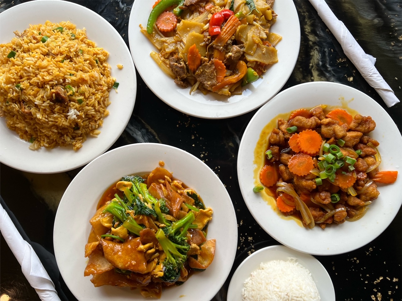 An overhead photo of four entrees from Sticky Rice in Champaign. Photo by Alyssa Buckley.