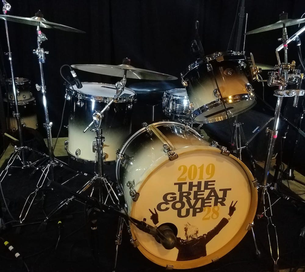 A close up shot of a drum set with a black background. The bass drum reads 