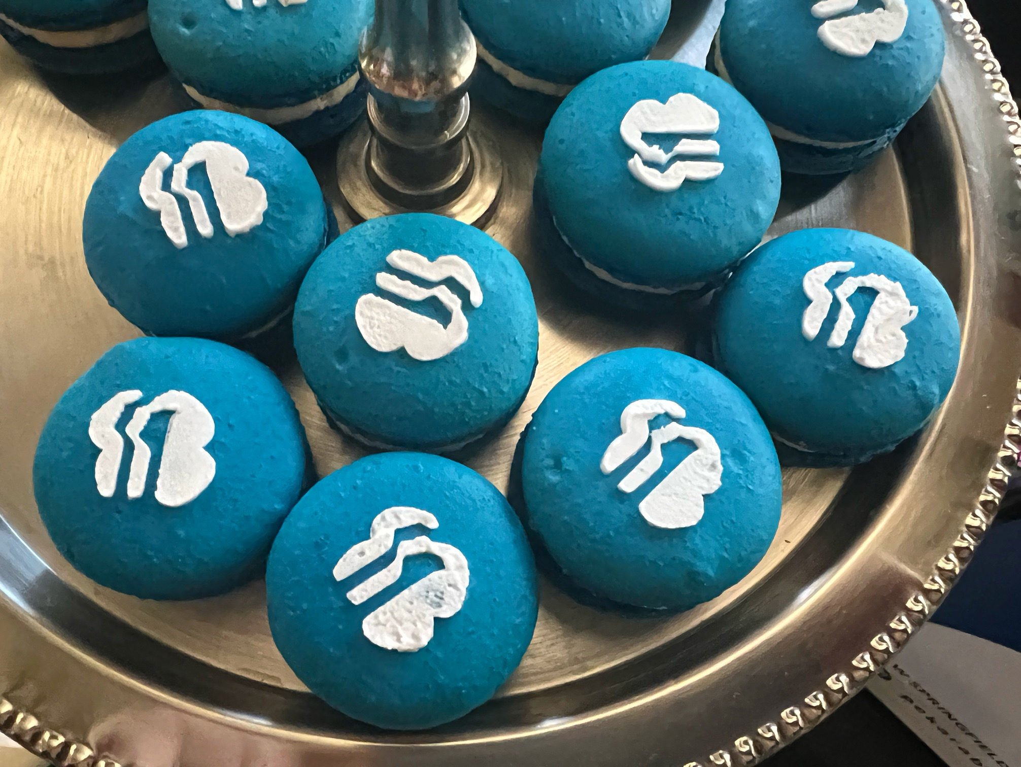 On a silver tiered holder, there are bright blue macarons with the Girl Scouts logo in white. Photo by Alyssa Buckley.