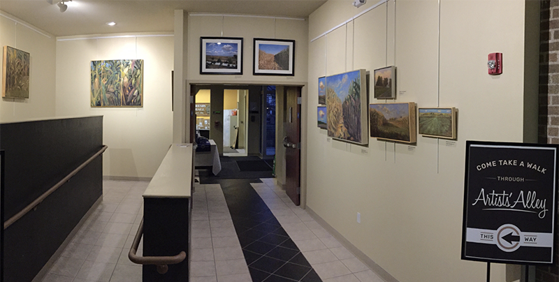 A photo of artist alley; a corridor with paintings hanging on the wall