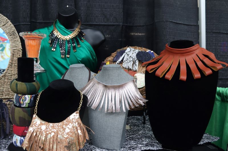 Several fringe necklaces are displayed on a table. There are also several thick bracelets stacked on top of each other. Photo by Maddie Rice.