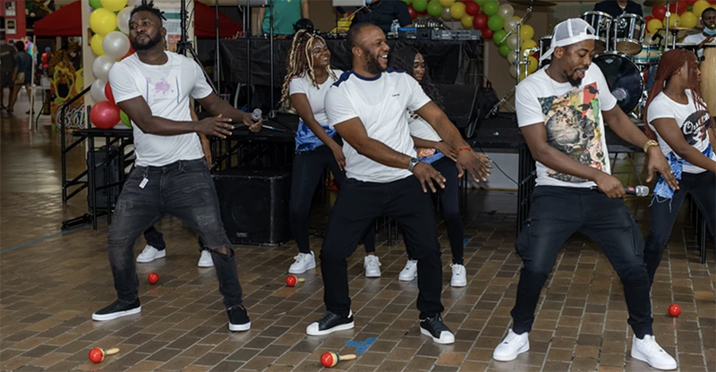 Black male and female dancers in white t-shirts and black pants dance inside Lincoln Square Mall.